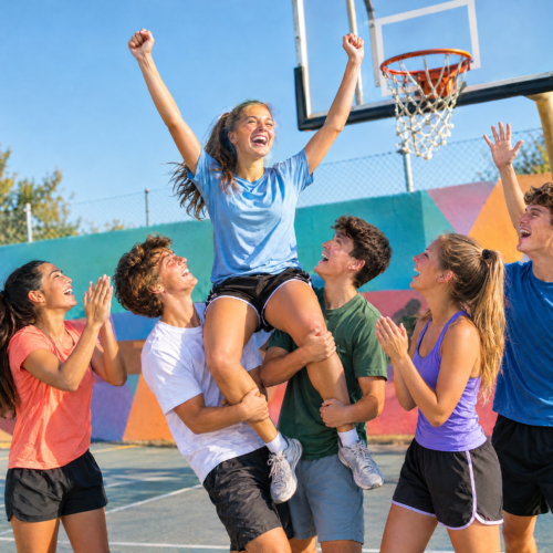 Jugendliche feiern auf dem Basketballplatz: Ein Mädchen wird nach einem Treffer von ihrem Team hochgehoben